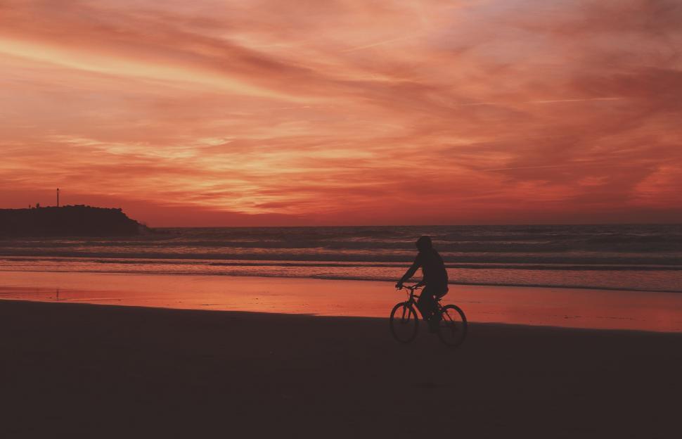 Free Image of Person Riding Bike on Beach at Sunset 