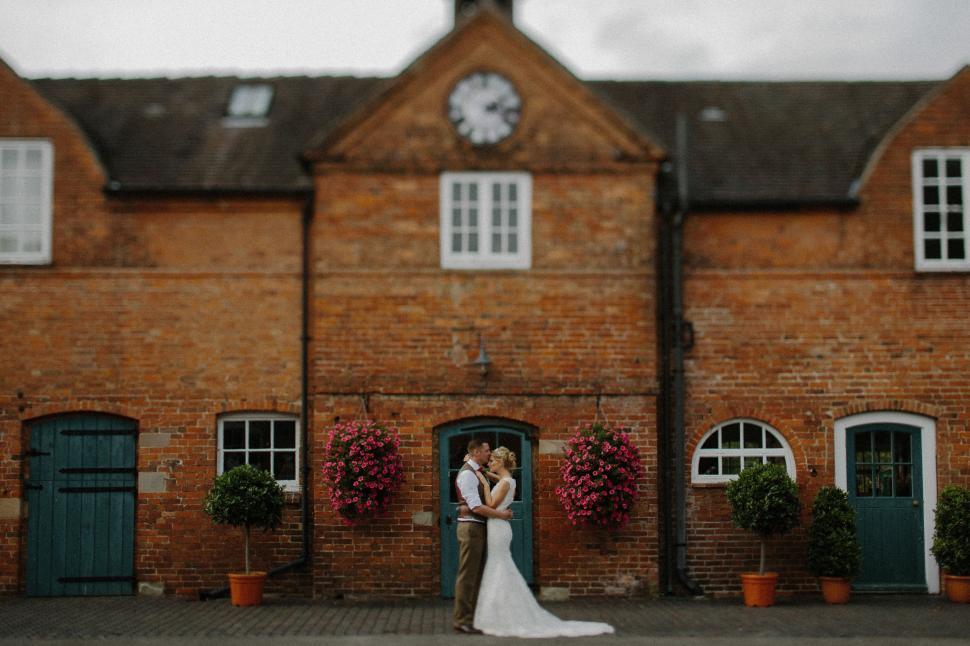 Free Image of Bride and Groom Standing in Front of Brick Building 