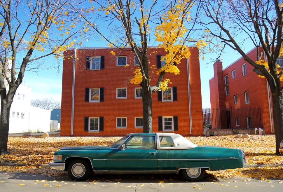 Free Image of Green Car Parked in Front of Red Building 