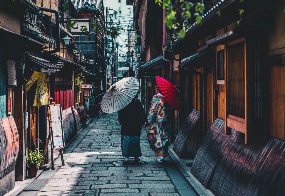 Free Image of Couple Walking Down Street Holding Umbrellas 