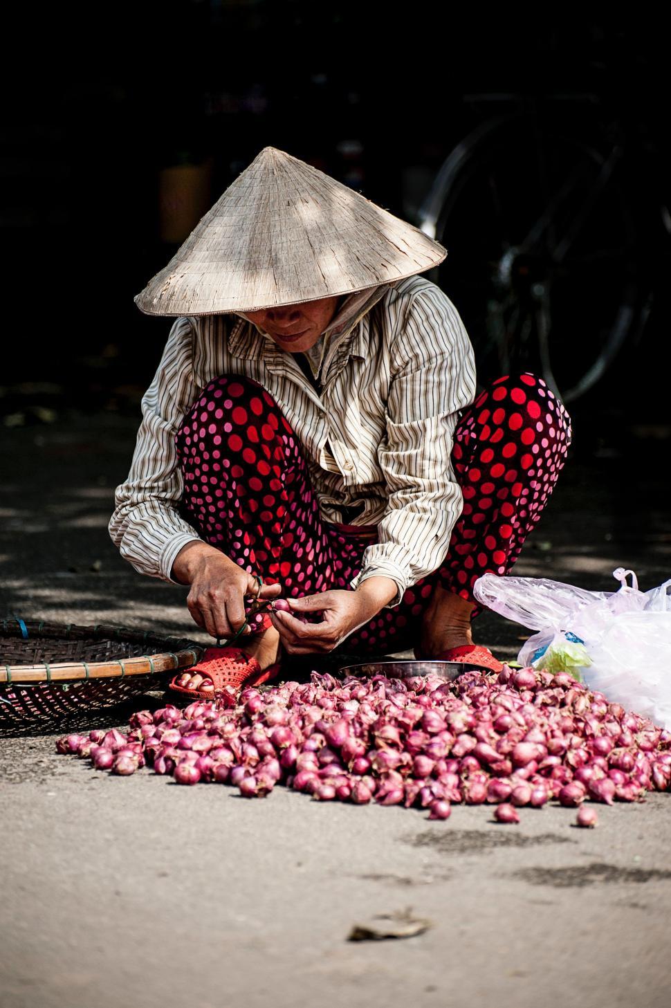 Free Image of Woman Sitting With a Bunch of Onions 