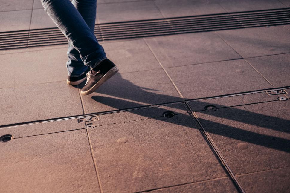 Free Image of Person Standing on Sidewalk With Shadow 