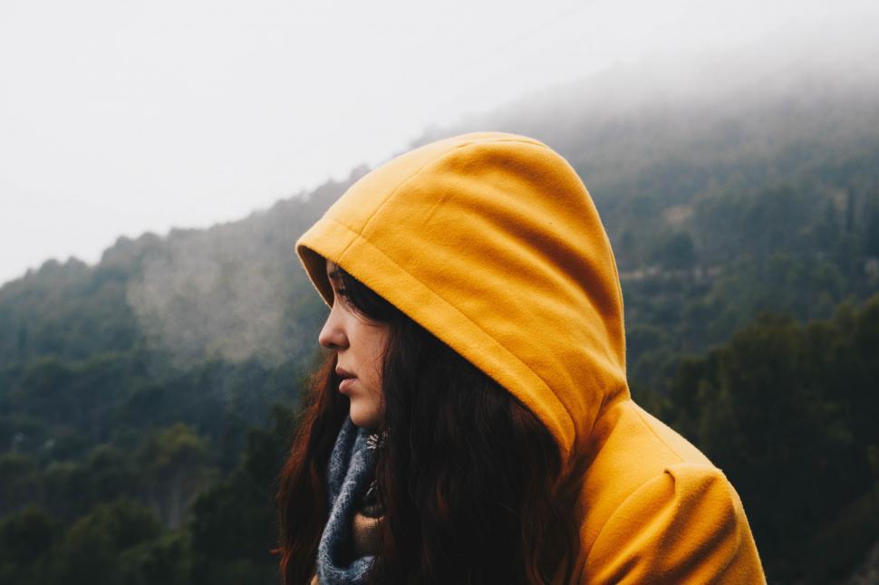 Free Image of Woman in Yellow Hoodie Looking Out Over Mountain 