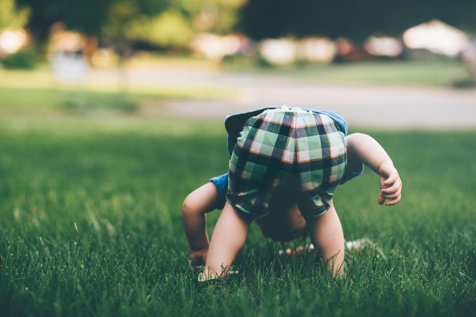 Free Image of Small Child in Plaid Shirt Crawling in Grass 