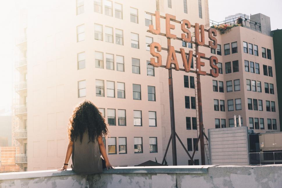 Free Image of Woman Sitting on Ledge in Front of Building 