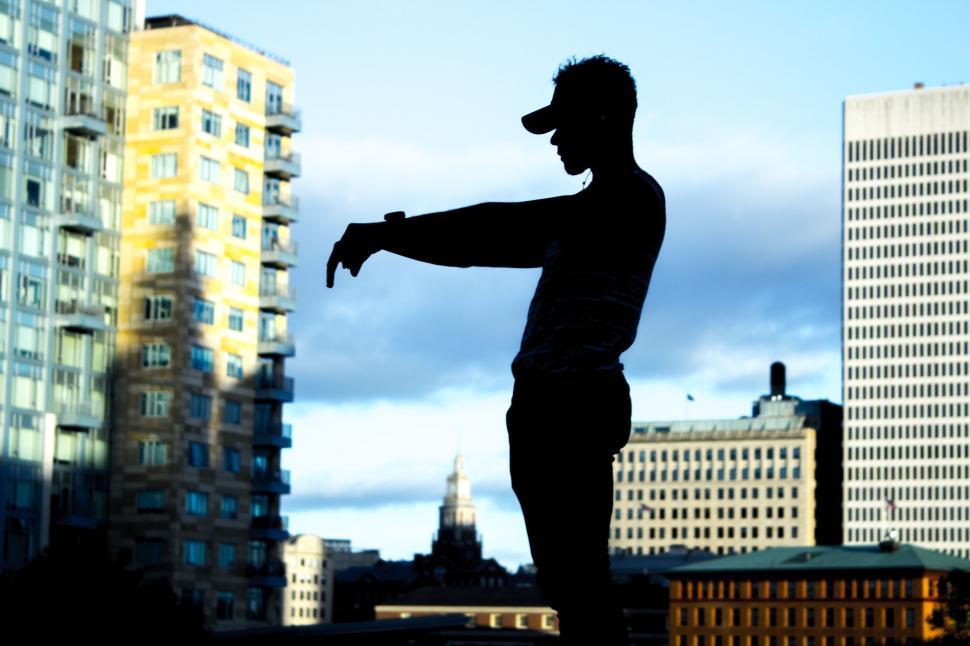 Free Image of Silhouette of Man Standing in Front of Tall Buildings 