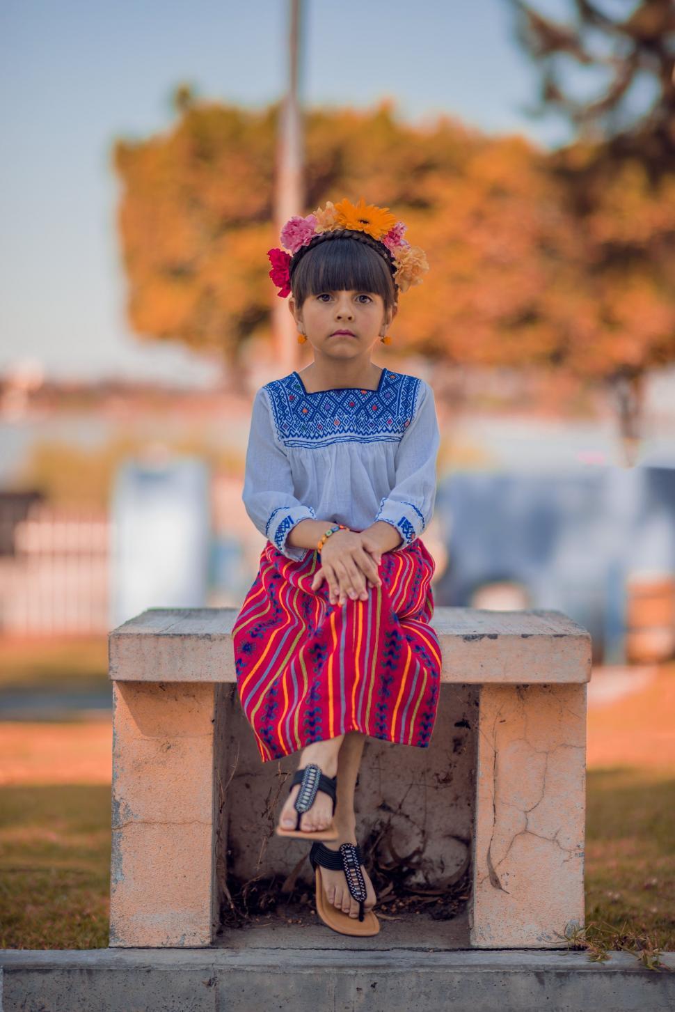 Free Image of Little Girl Sitting on Top of Cement Bench 