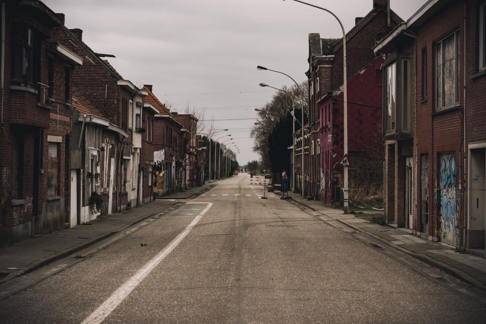 Free Image of Empty Street With Brick Buildings Under Cloudy Sky 