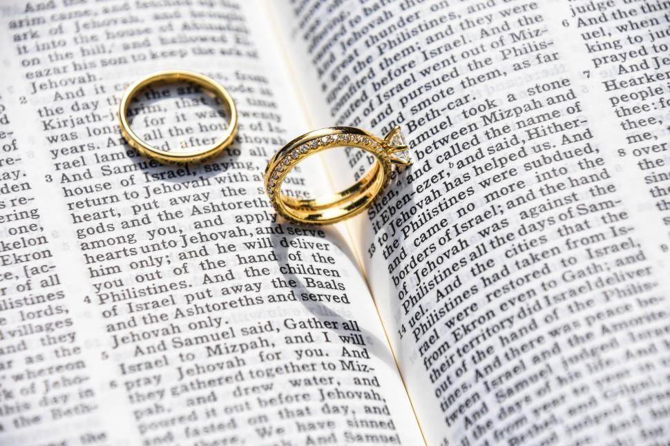 Free Image of Two Wedding Rings Resting on an Open Bible 