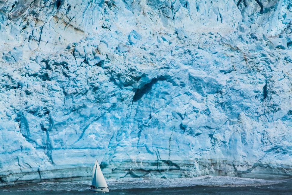 Free Image of Sailboat Navigating Near Large Iceberg. 