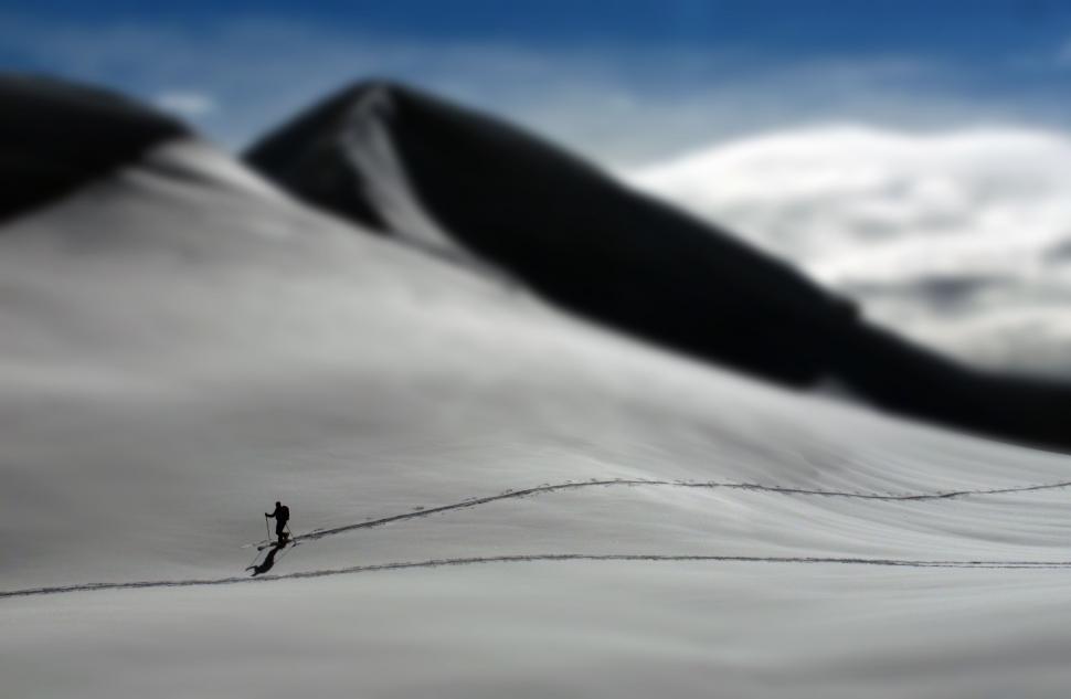 Free Image of Man Walking Across Snow Covered Slope 