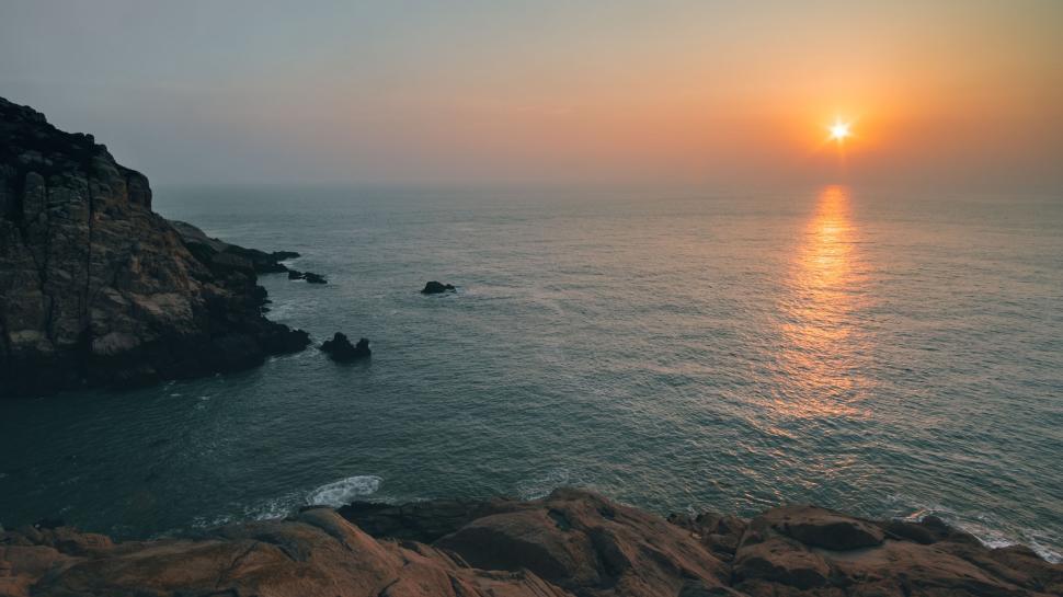 Free Image of Sun Setting Over Ocean and Rocks 
