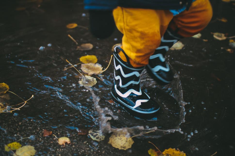Free Image of Black and Yellow Shoes Standing in Puddle 