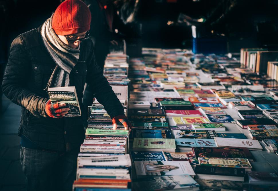 Free Image of Man Standing in Front of Table Covered in Books 