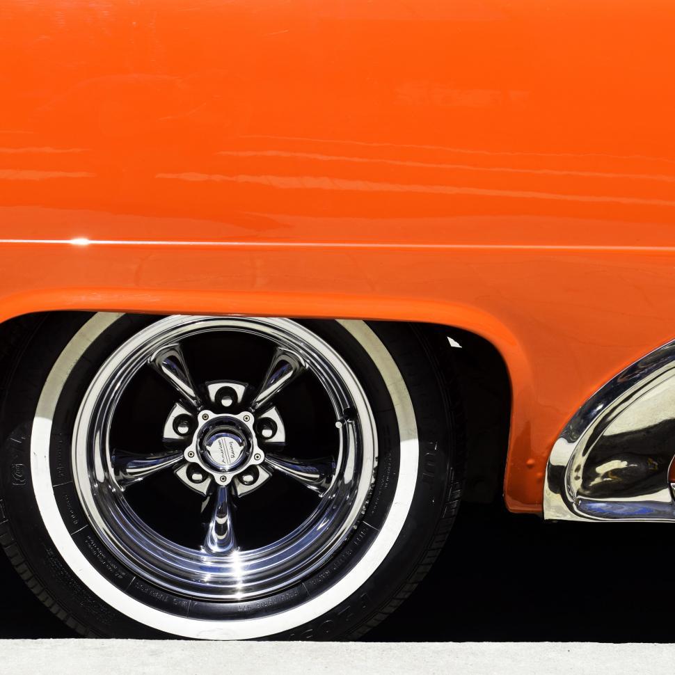 Free Image of Orange Car With Chrome Rims Parked on Street 