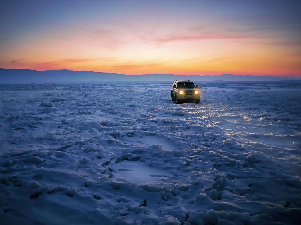 Free Image of Car Driving Through Snow at Sunset 