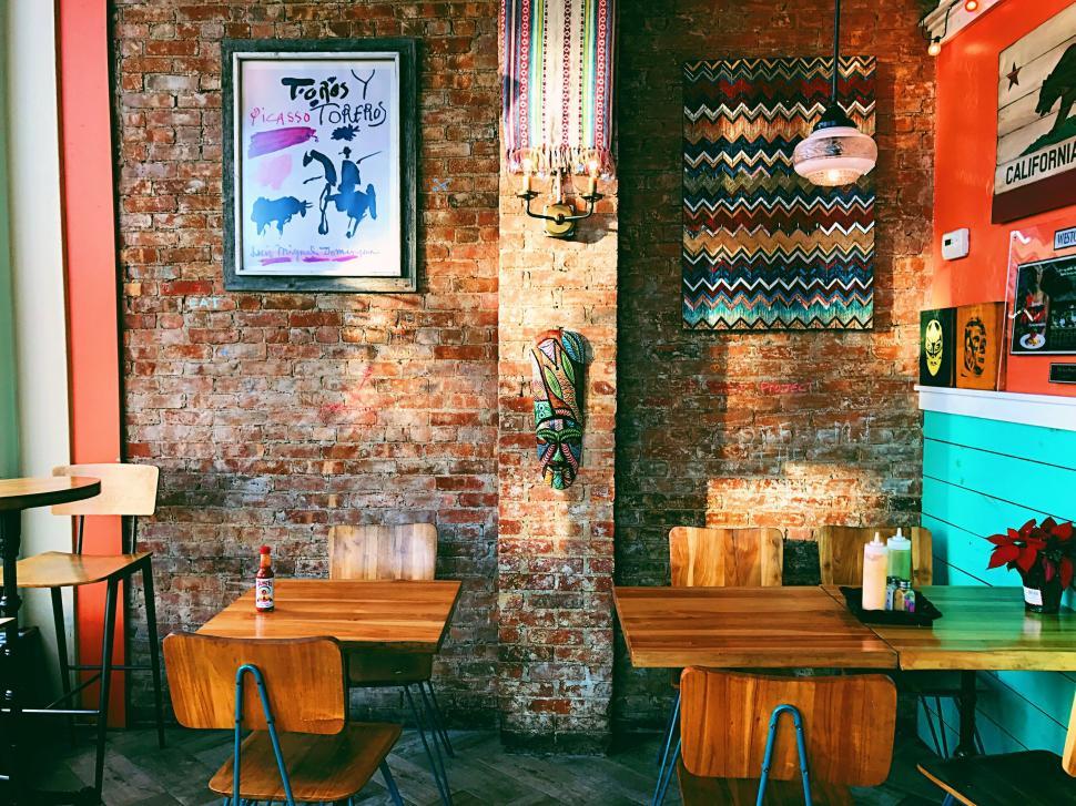 Free Image of Brick Wall in a Restaurant With Wooden Tables and Chairs 