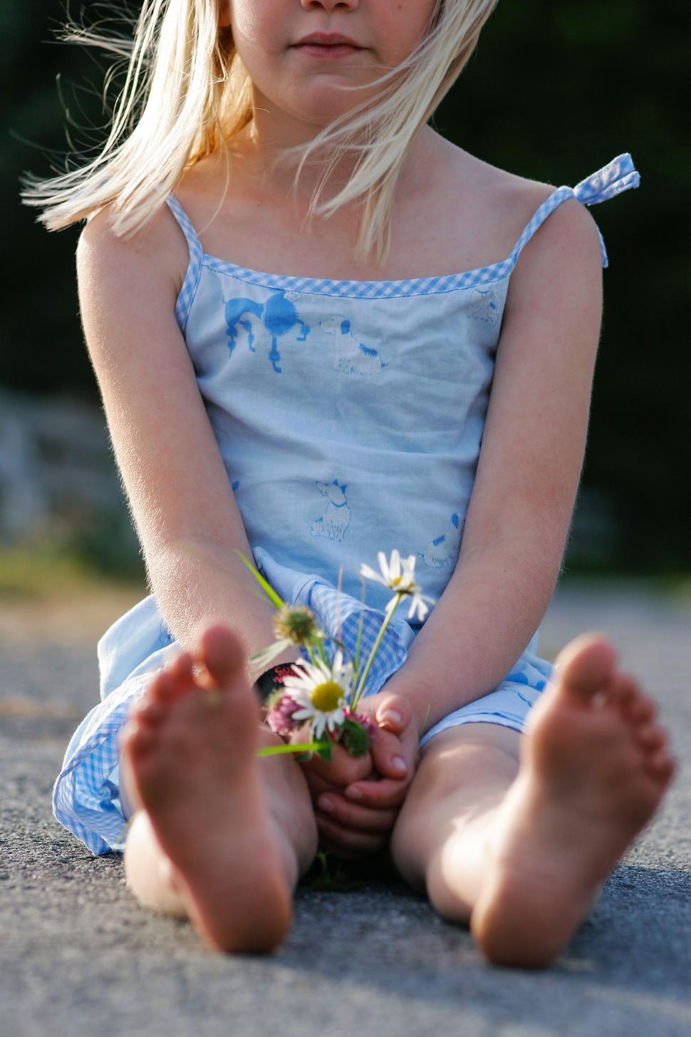 Free Image of Young Girl Sitting on Ground Holding Flower 