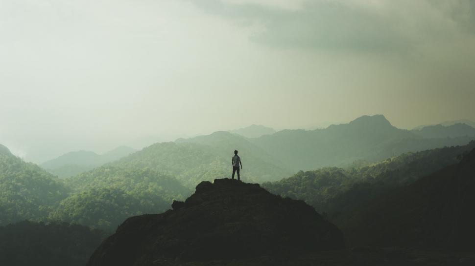 Free Image of Man Standing on Mountain Beside Giant Object 