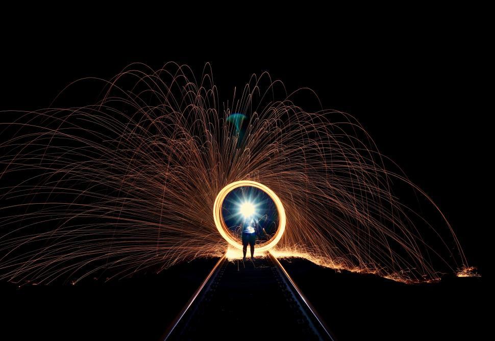 Free Image of Person Standing on Train Track With Fireworks in Background 