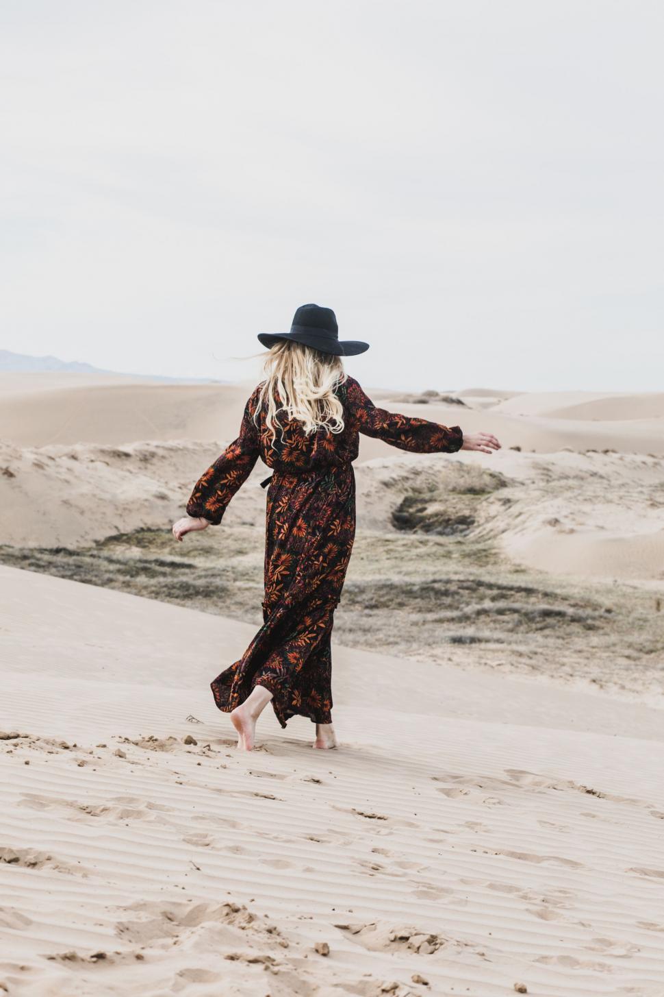 Free Image of Woman in Long Dress and Hat Walking in Sand 