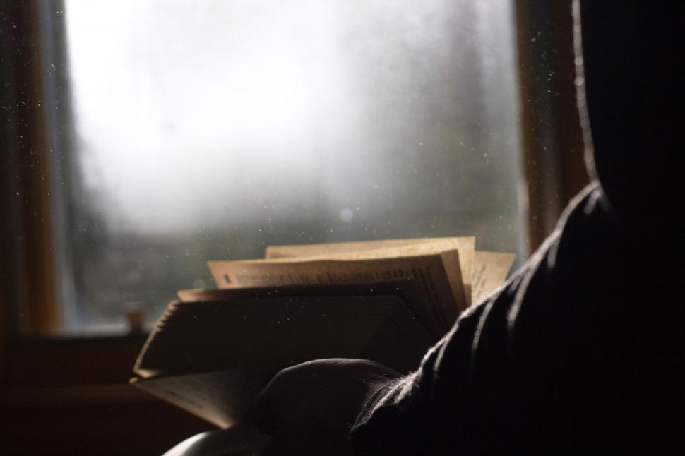 Free Image of Person Reading Book in Front of Window 