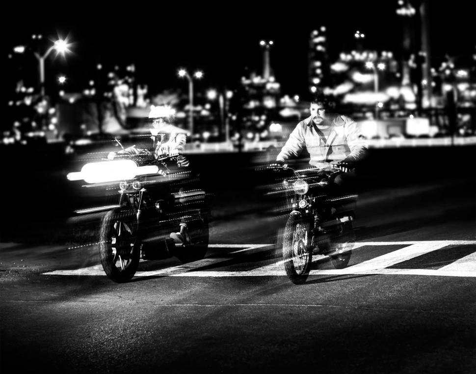 Free Image of Two Men Riding Motorcycles Down a Street at Night 