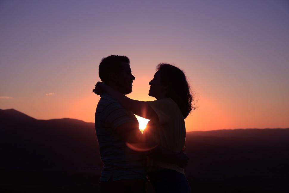 Free Image of Man and Woman Standing in Front of Sunset 