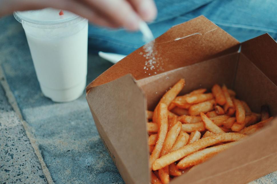 Free Image of Person Eating French Fries Out of a Box 