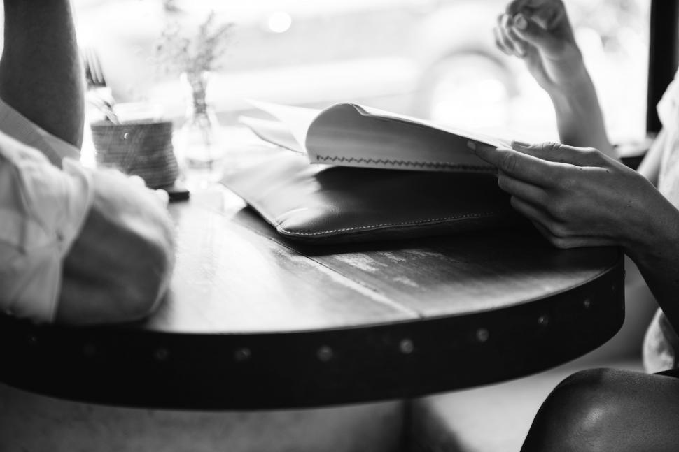 Free Image of Person Sitting at Table Reading a Book 