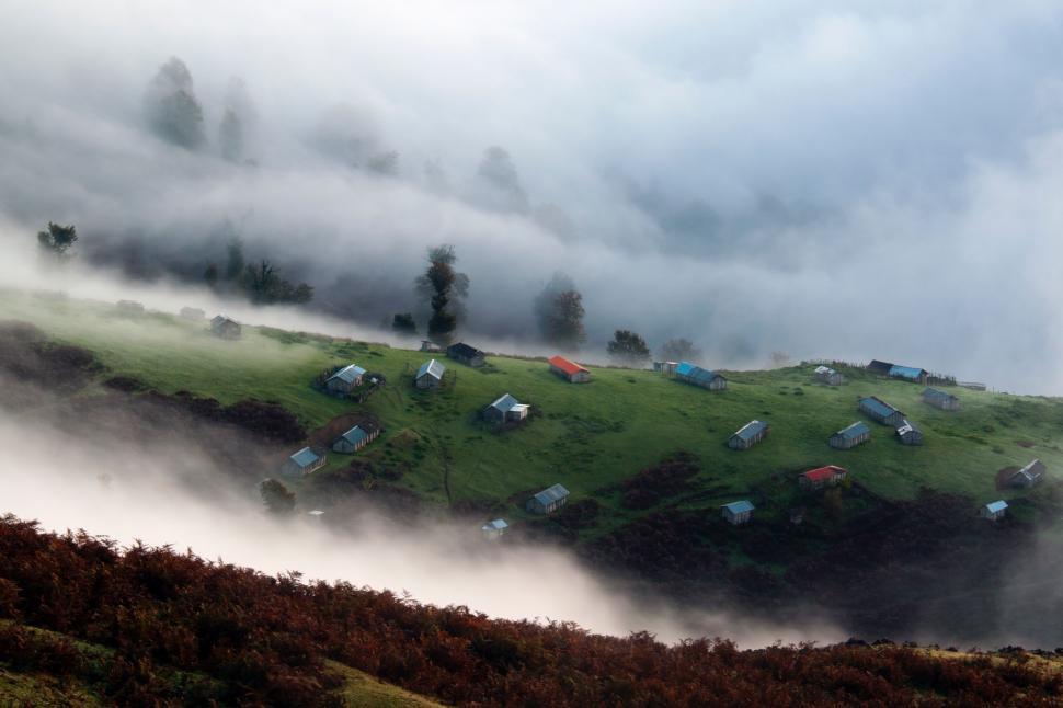 Free Image of Green Hill Shrouded in Fog and Clouds 