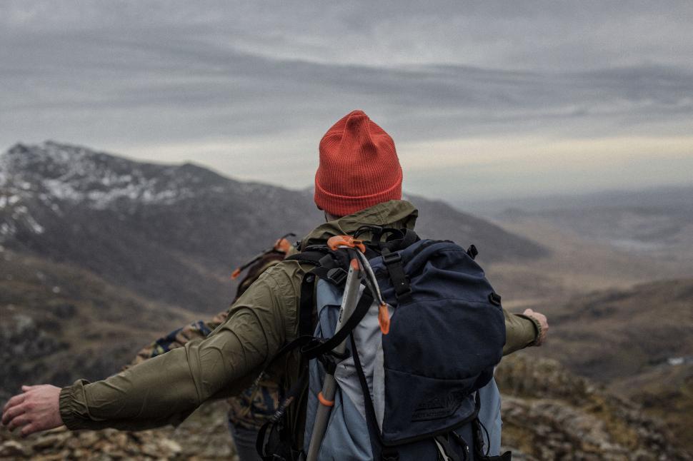 Free Image of Person With Backpack and Red Hat Standing on Mountain 