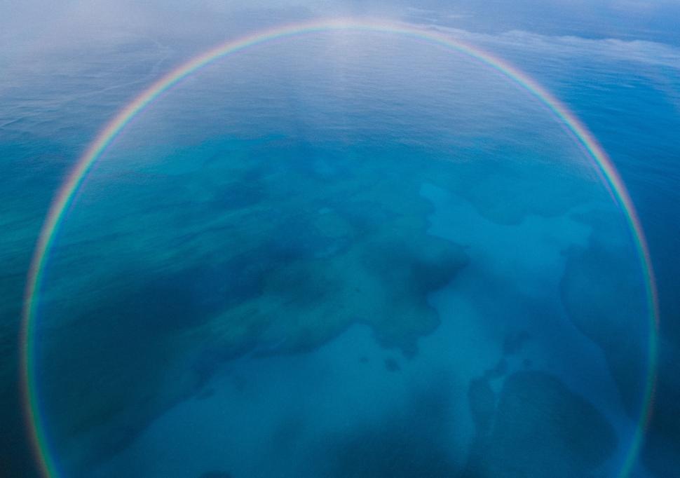 Free Image of Airplane Flying Over Ocean With Rainbow in Sky 