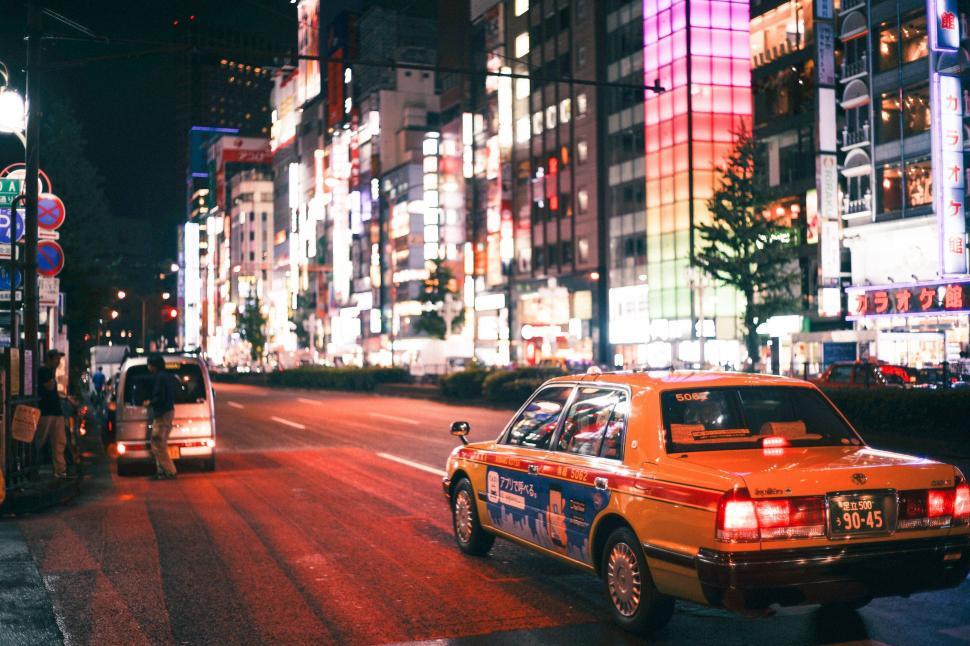 Free Image of Taxi Cab Driving Down a Street Next to Tall Buildings 