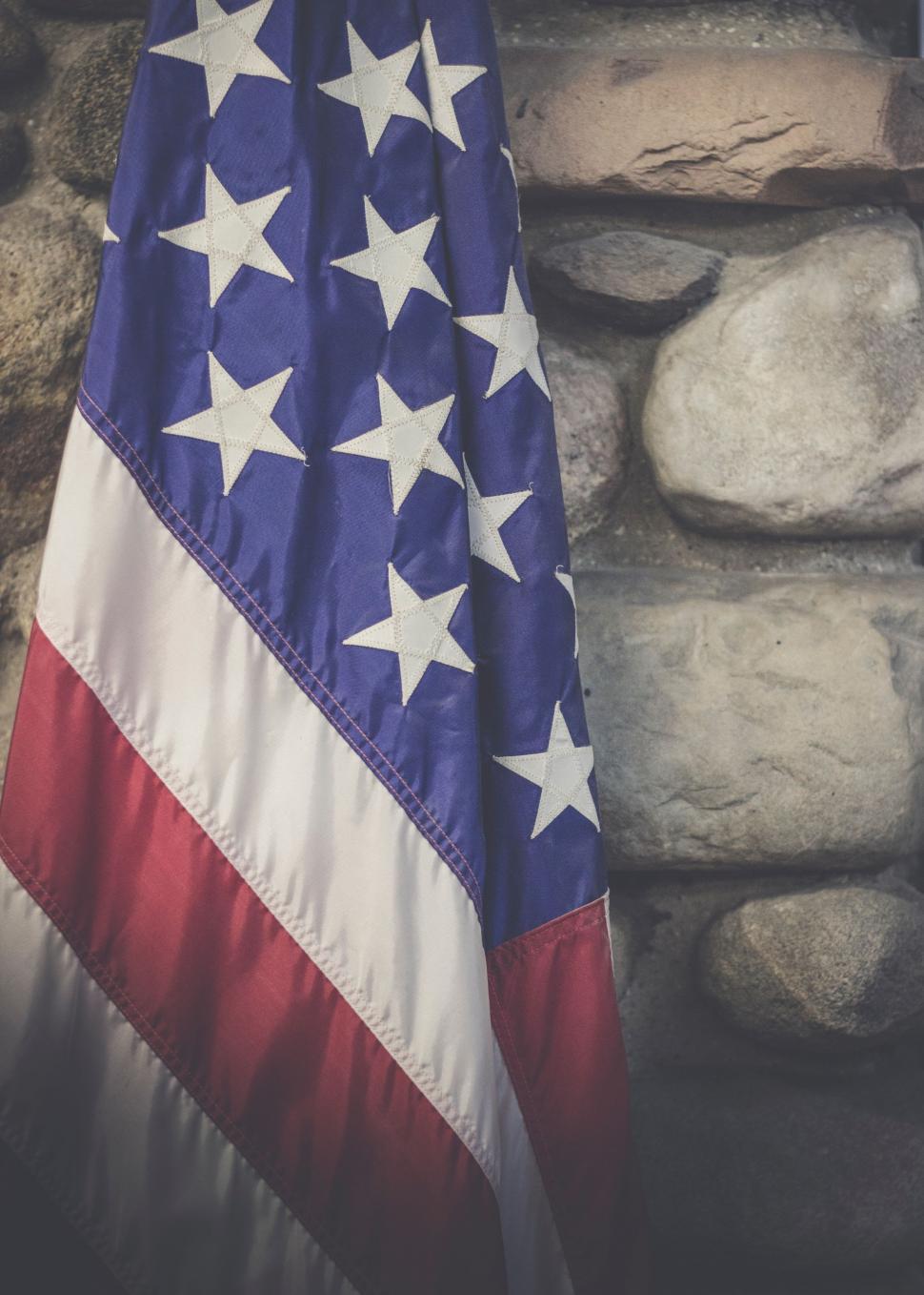 Free Image of American Flag Hanging on Stone Wall 