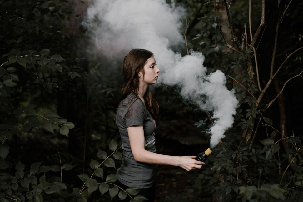 Free Image of Woman Standing in Front of Smoke-Filled Forest 