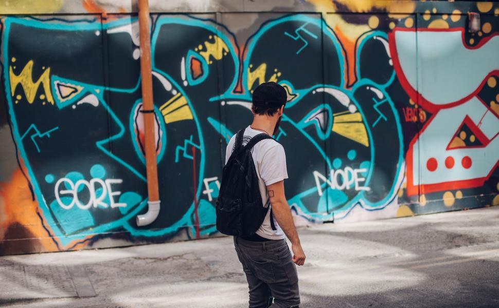 Free Image of Man Walking Next to Graffiti-Covered Wall 