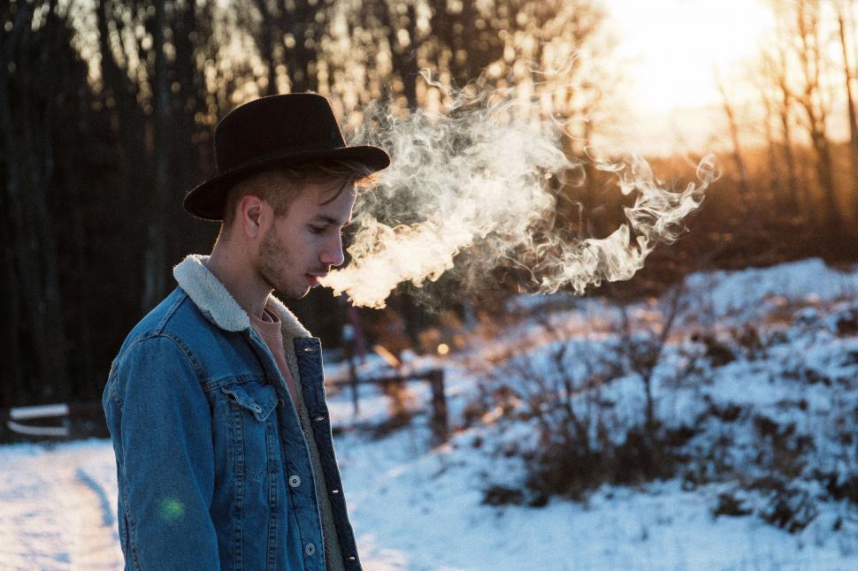 Free Image of Man in Blue Jacket and Hat Smoking a Cigarette 