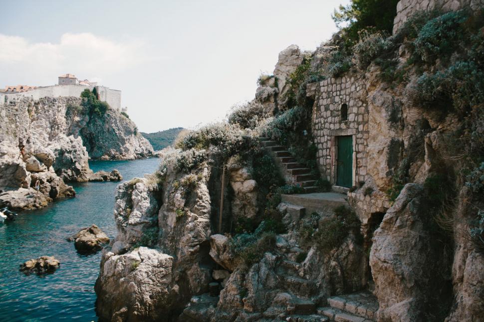Free Image of Rocky Cliff With Stairs Leading Up to a Building 