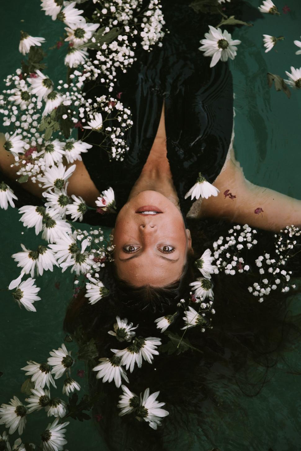 Free Image of Woman Floating in Water Surrounded by Flowers 