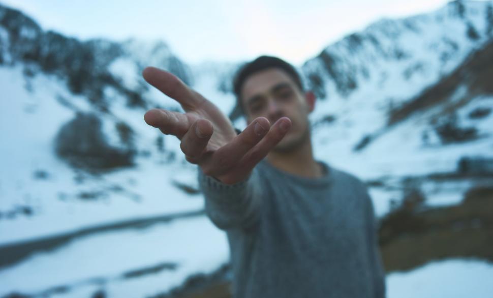 Free Image of Man Gesturing in Front of Mountain 