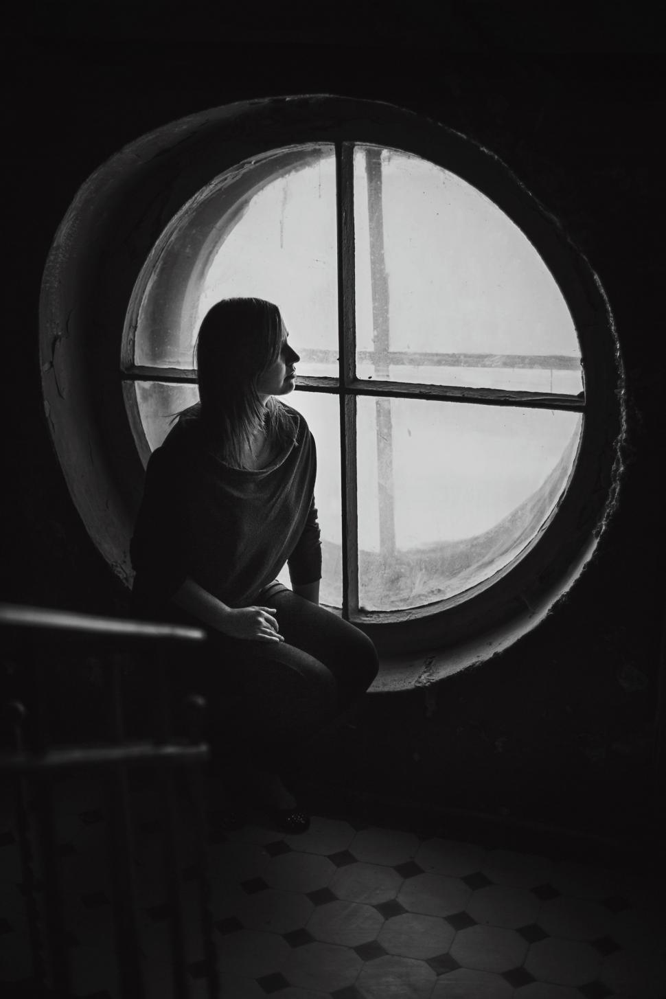 Free Image of Woman Sitting in Front of Round Window 