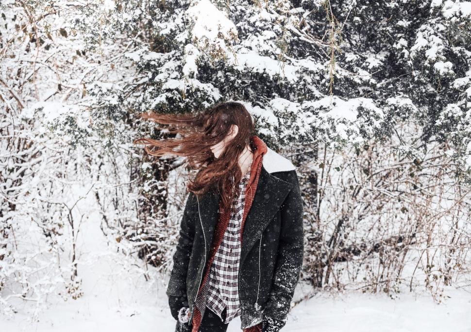 Free Image of Woman Standing in Snow With Blowing Hair 