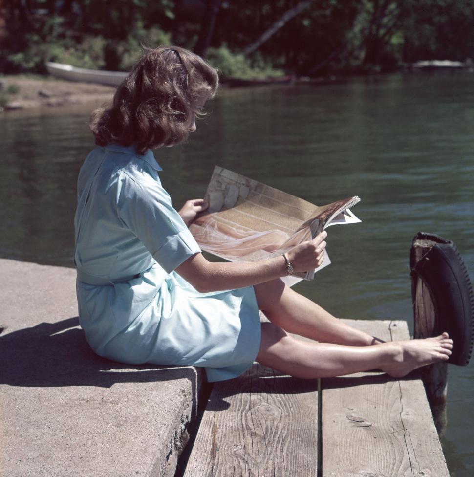 Free Image of Woman Sitting on Dock Reading a Book 