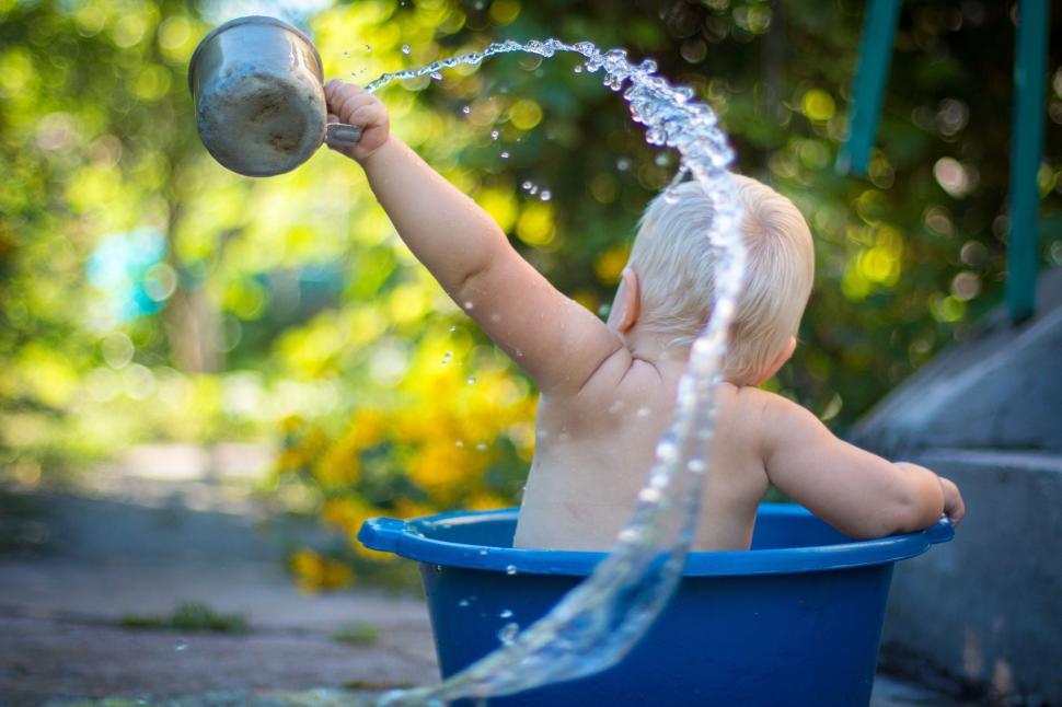 Free Image of Baby Playing in Blue Tub With Water 