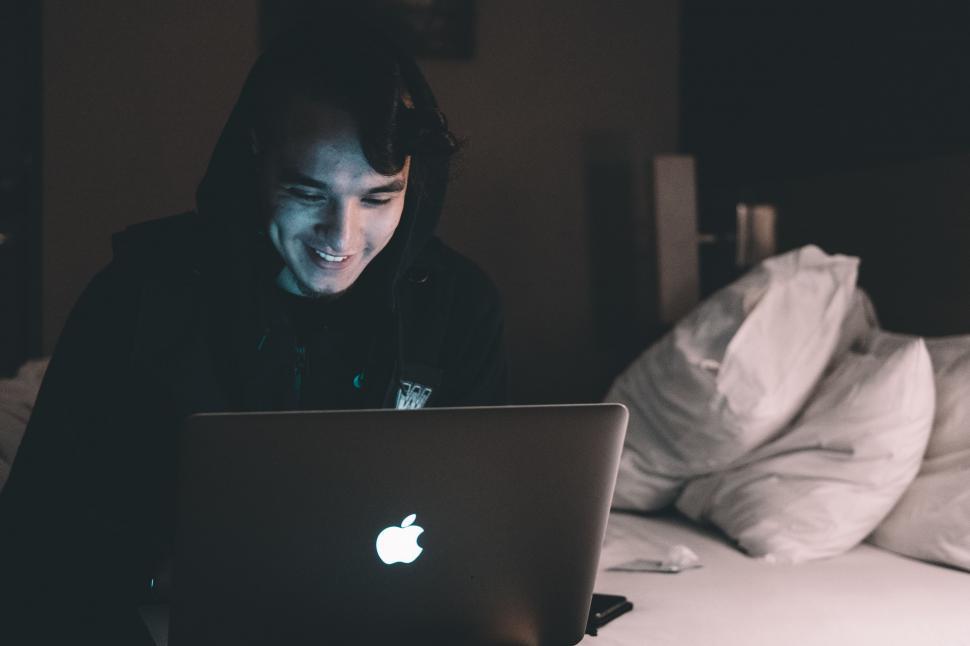 Free Image of Man Sitting on Bed Using Laptop Computer 