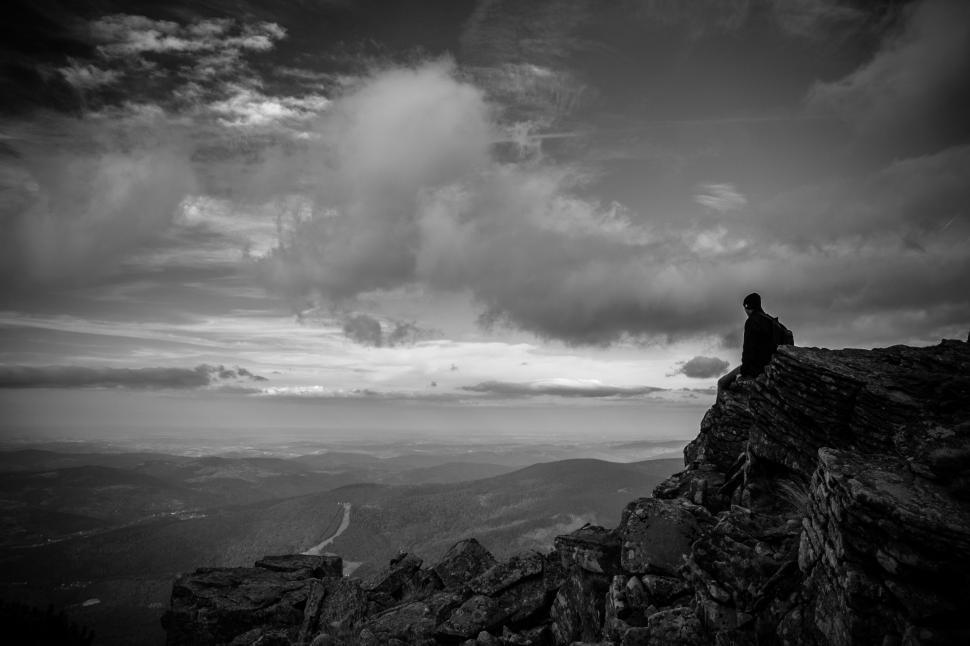Free Image of Man Sitting on Mountain Summit Under Cloudy Sky 