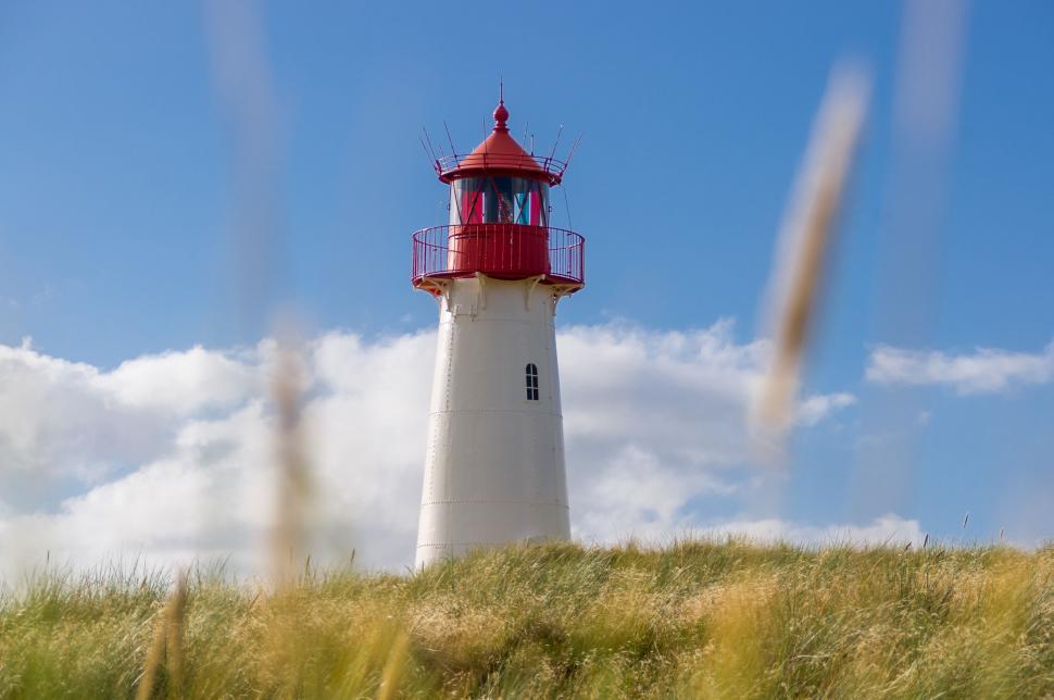 Free Image of Red and White Lighthouse on Grassy Hill 