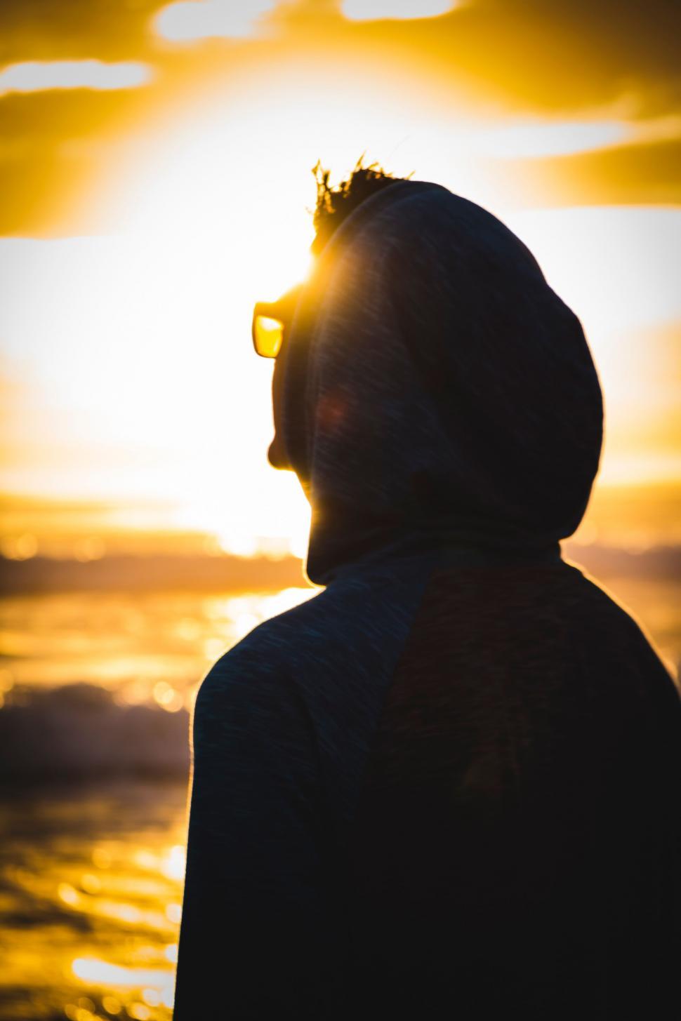 Free Image of Person in Hoodie Standing in Front of Sunset 