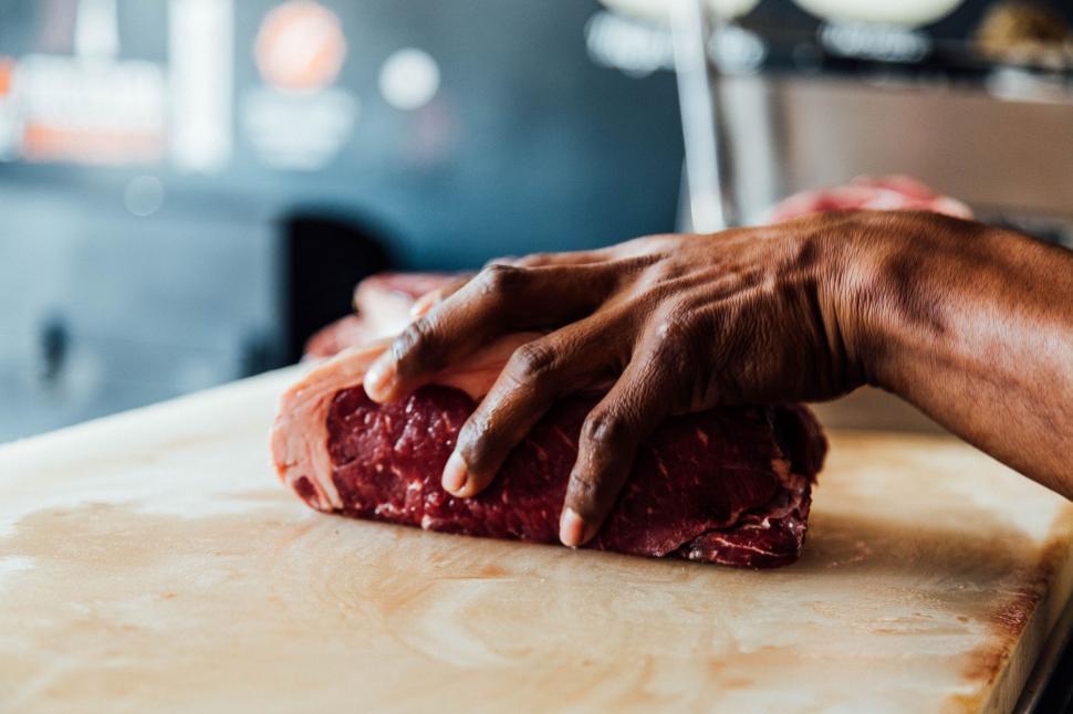 Free Image of Person Cutting Up Meat on Cutting Board 